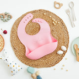 Pink Silicone toddler Bib with food catching pocket "personalized" laser engraved with child's name in cursive script.