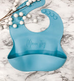 Blue silicon baby bib personalized laser engraved name across the front, the bib has a food catching pocket on the front to help keep baby and highchair mess free.