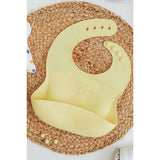 Yellow silicone bib laser engrave with the name Riley Lane on textured charger by Legacy and Light