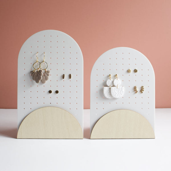 Modern arched earring holders for studs and dangles, featuring pegboard-style holes and natural wood bases. Includes display of handmade polymer clay and gold earrings. Perfect for jewelry organization or retail display. Shown in large and medium sizes on a minimal backdrop.