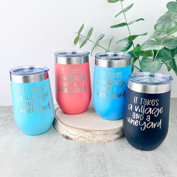Four 16 ounce wine tumlers with 'It takes a Village and a Vineyard' laser engraved.  the tumblers are mint, coral, blue, and black.