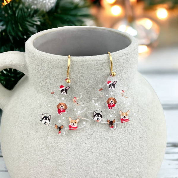 Christmas Earrings in the shape of a Christmas tree hanging on a vase with a Christmas tree in the background
