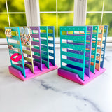 Colorful jewelry display stands on a marble surface with a window in the background.