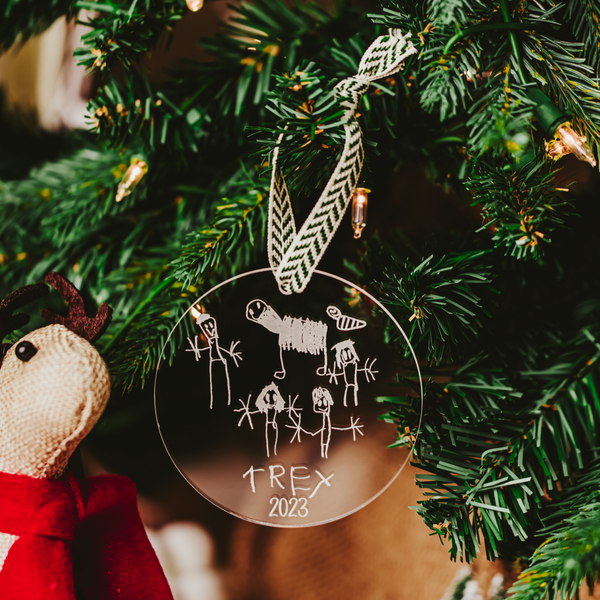 A clear acrylic ornament with a child's family portrait laser engraved into the acrylic hanging on a Christmas Tree