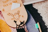 Wooden tooth fairy box with a cartoon tooth design on a textured surface.