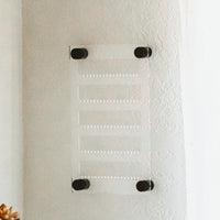 6 inch by 10 inch clear acrylic earring holder hanging on a textured wall with black screws by legacy and Light