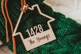 Wooden House shaped ornament cut with the house number and engraved with The Youngs with a Suede Tie placed on a Green Christmas Stocking 