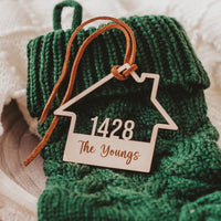 Wooden House shaped ornament cut with the house number and engraved with The Youngs with a Suede Tie placed on a Green Christmas Stocking 