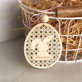Laser cut and engraved natural Birch wood basket name tag. Egg shaped with intricate cut pattern and a floppy eared bunny in the center personlized name in the center of the floppy eared bunny. Tag is atttached to a wire basket.