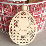 Laser cut and engraved natural Birch wood basket name tag. Egg shaped with intricate cut pattern and a chick in the center personlized name in the center of the chick. Tag is atttached to a wire basket.
