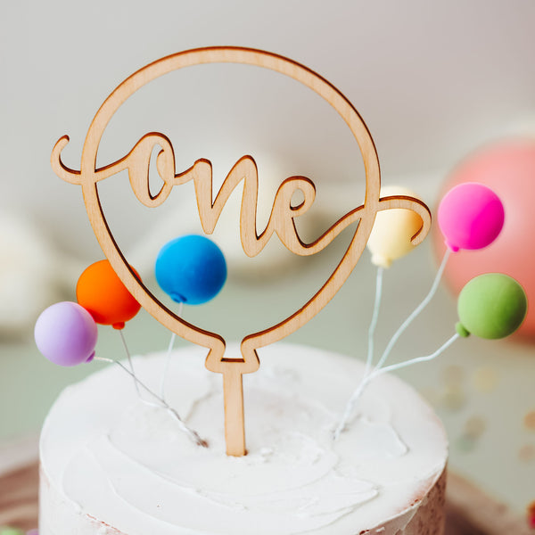 Balloon Shaped laser cut cake topper. Displaying the word "One" scroll cut across the center of the balloon.