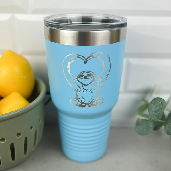 Blue 30 ounce tumbler with a sloth with arms in a heart shape laser engraved into the powder coating