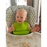 Baby with engraved bib in high chair with cereal