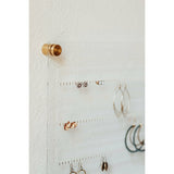 Clear acrylic earring organizer with gold hardware shown with several pairs of earrings of different styles