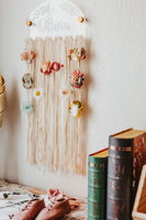 Alternate view showing how the hair bows are hung on the cotton strings that hang from the half acrylic circle. On a white background and book accents.