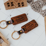 Dark stained wood keychain showing the laser engraved "Coffee, Contracts and Closings" on the front. Gold colored keyring is secured to the wood keychain by a vegan leather strap secrured with a gold colored metal stud. 