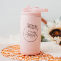 Matte Blush twelve-ounce hot and cold drink tumbler with flip up straw and the front is laser engraved with "Will You be my Flower Girl?" encircled with a flower wreath border.